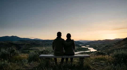 Deux silhouettes assises côte à côte face à un paysage au crépuscule, symbolisant la différence entre le bonheur affiché et le bonheur réel dans un couple