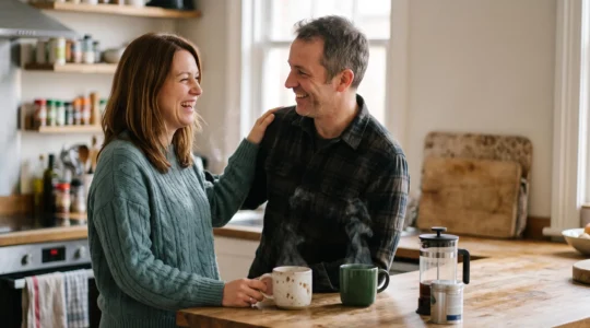 Couple souriant partageant un moment de complicité authentique à la lumière du matin, symbole d'une relation vivante après plusieurs années