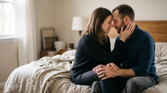 Couple assis proche l'un de l'autre dans une lumière douce du matin, partageant un moment de dialogue intime et bienveillant sur leur vie de couple.