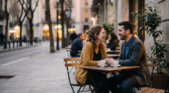 Couple souriant partageant un moment complice en terrasse au crépuscule, symbole d'une rencontre prometteuse évoluant vers une relation stable